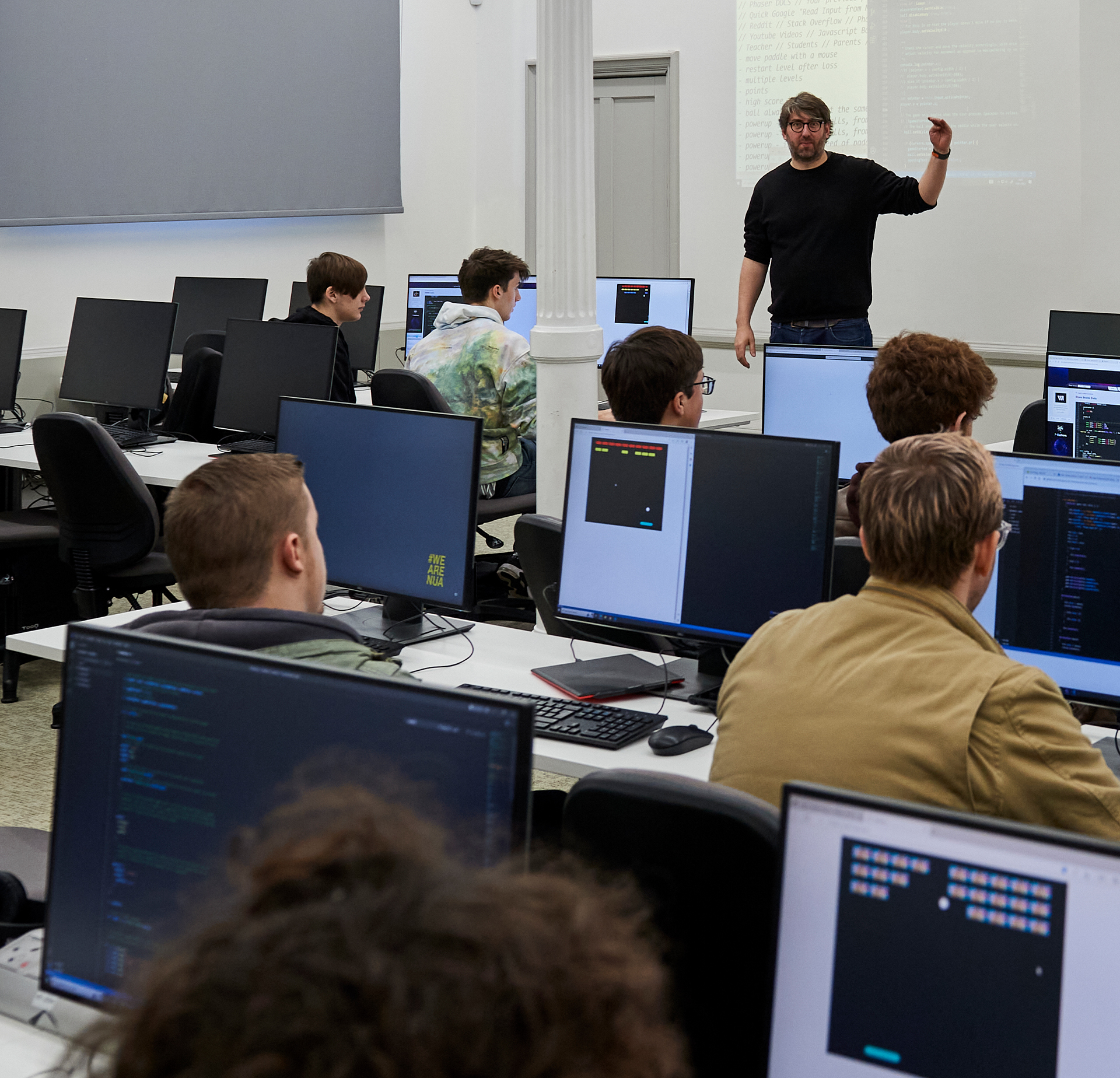 Technician teaching a Games Development workshop with students working on computers.
