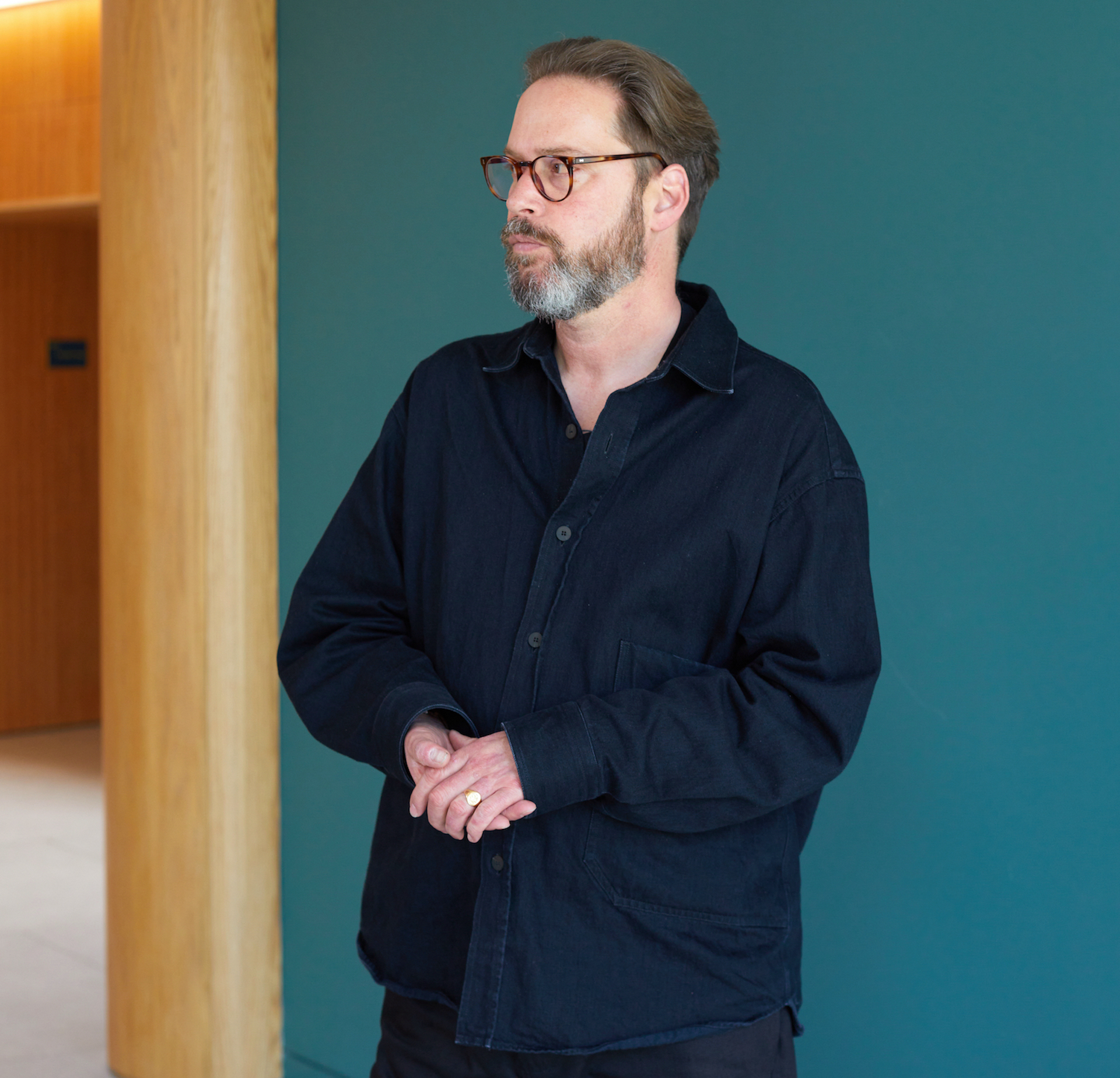 Profile image of Liam Wells wearing a dark navy shirt stood against a teal coloured wall.