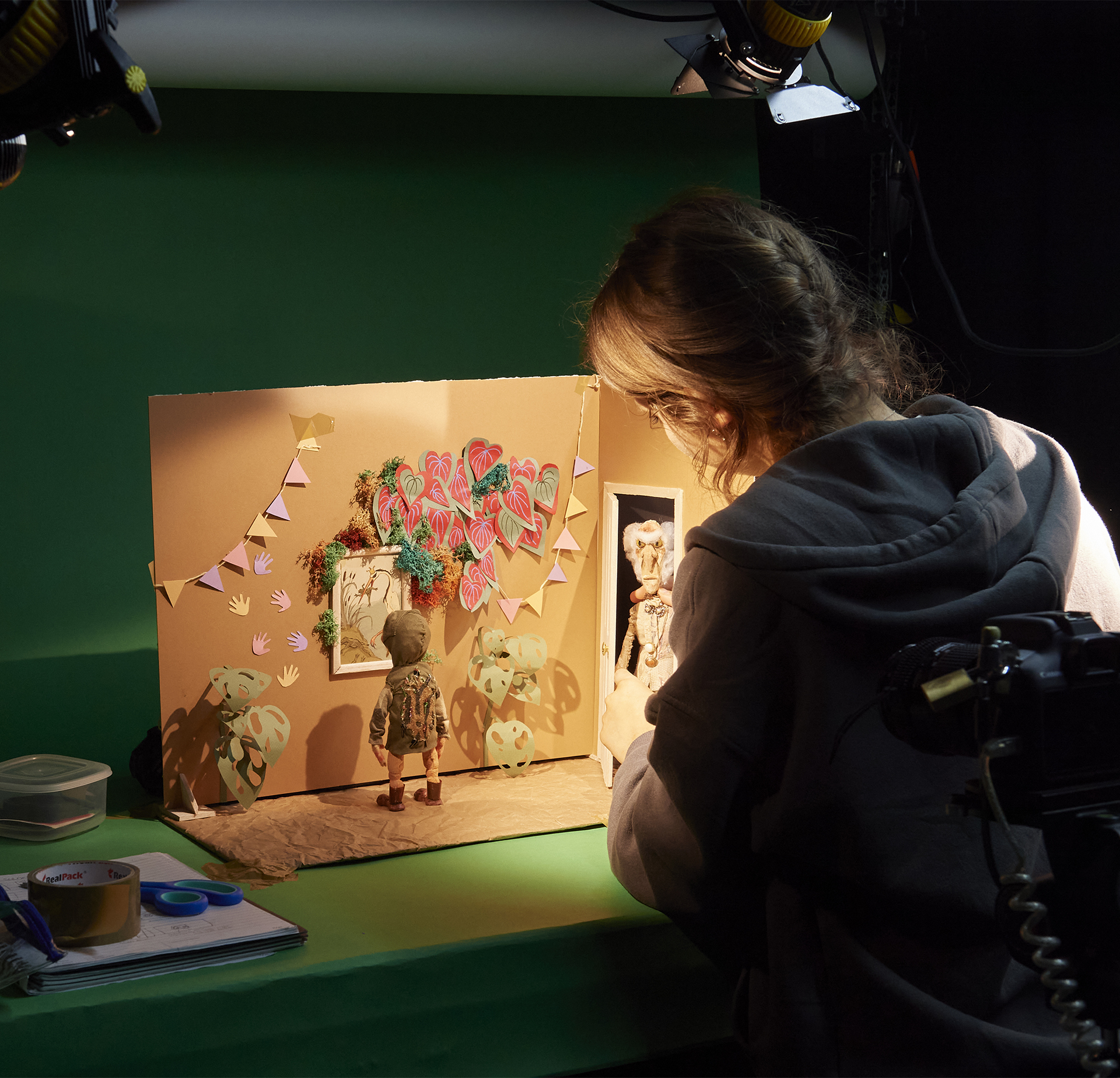 Animation student working on a stop motion set against a green backdrop.