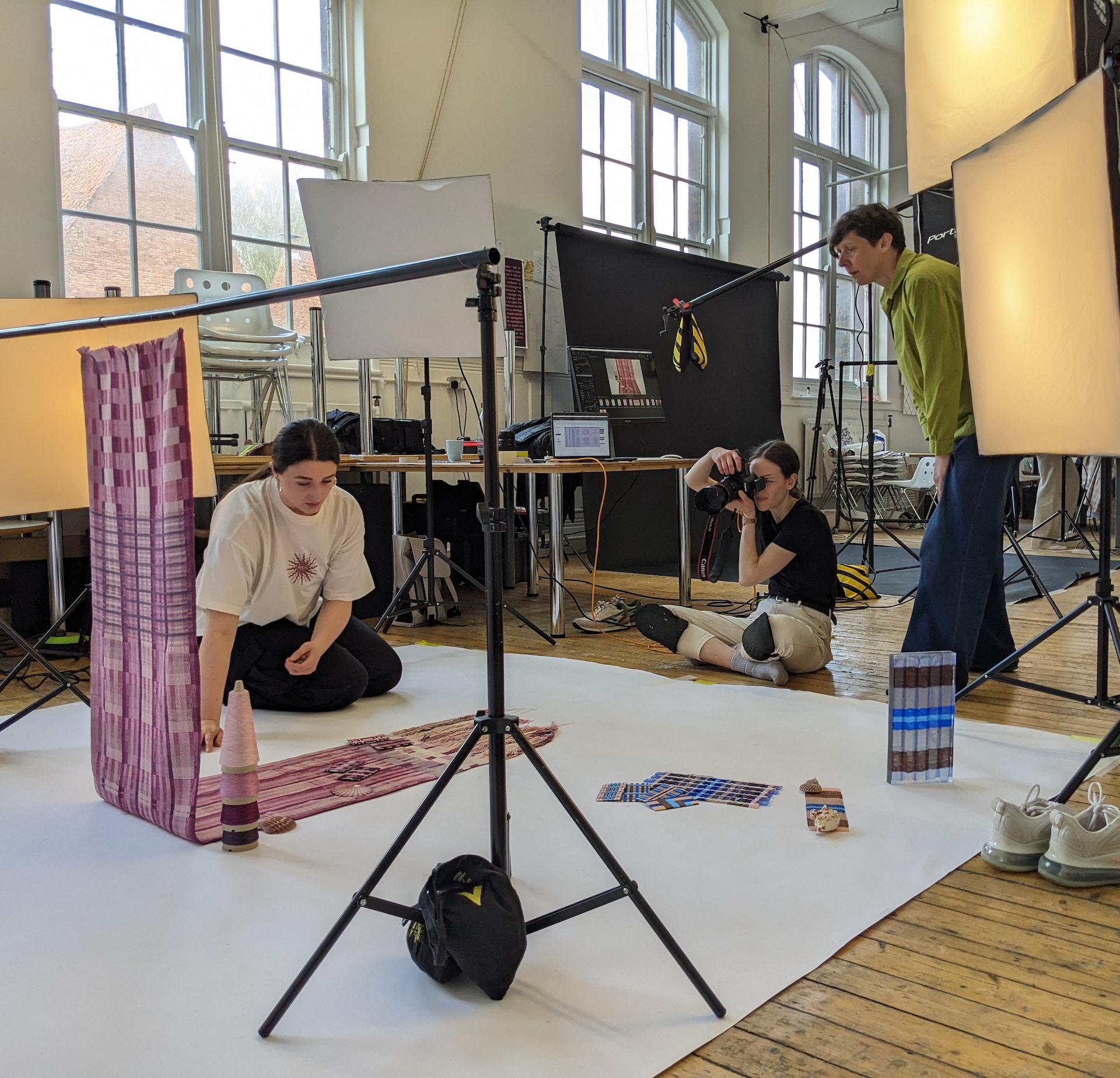 A student arranging their purple draped fabric on a stand in a photography shoot.