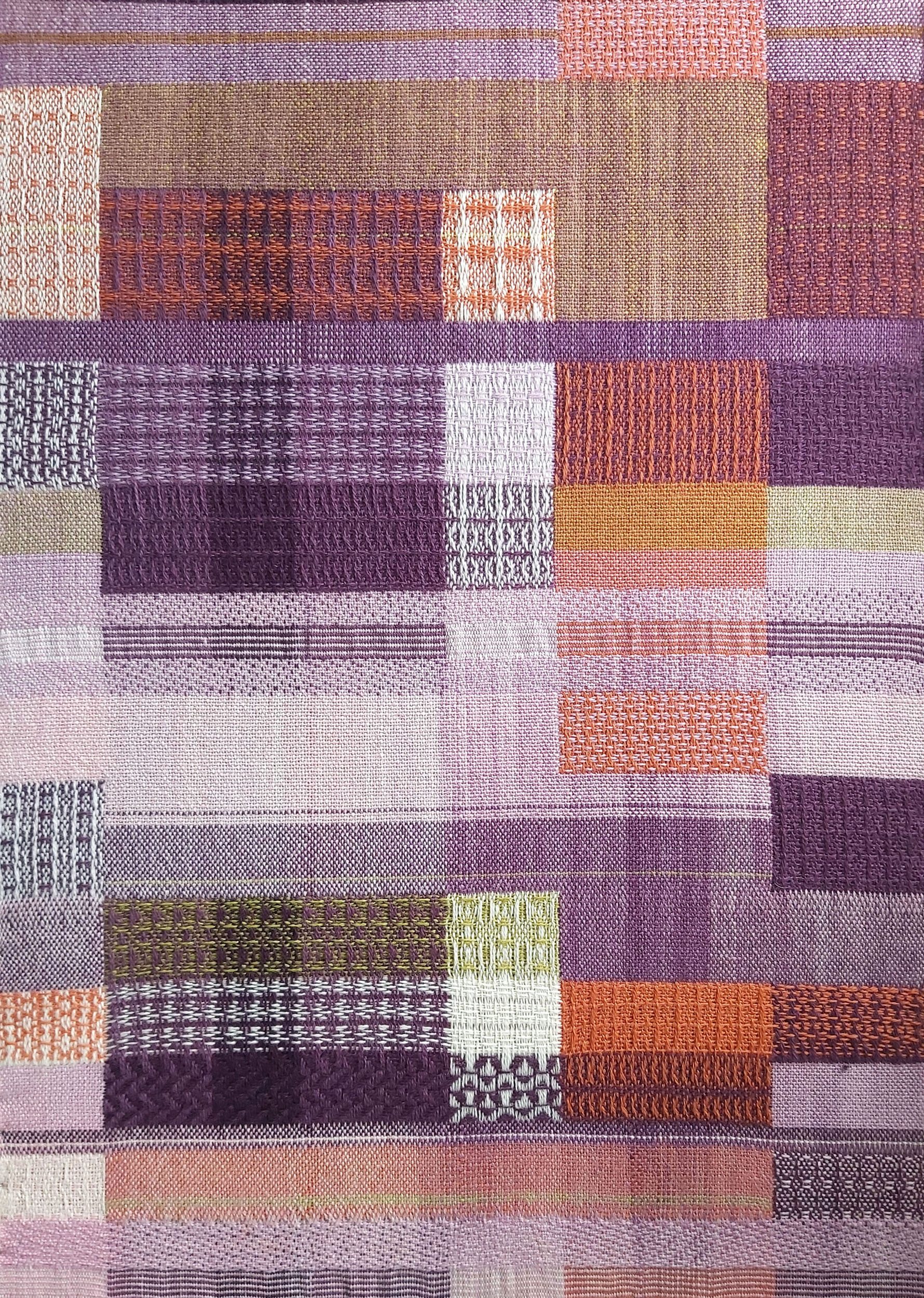 Textured abstract woven design in mainly plum and orange with multicoloured highlights.