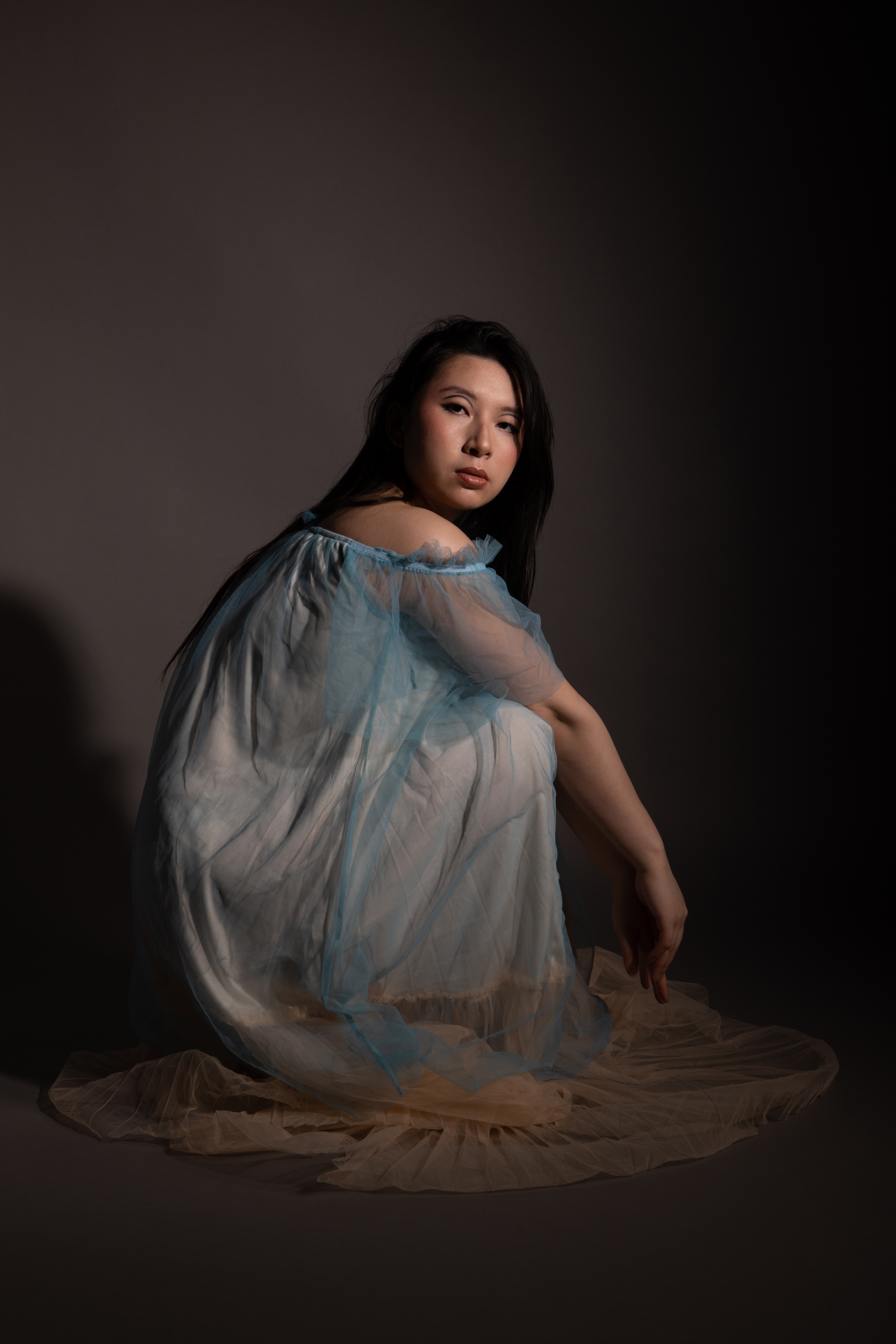 BA Photography work by Beth Unsworth shows an image of an Asian woman crouching in a blue dress.