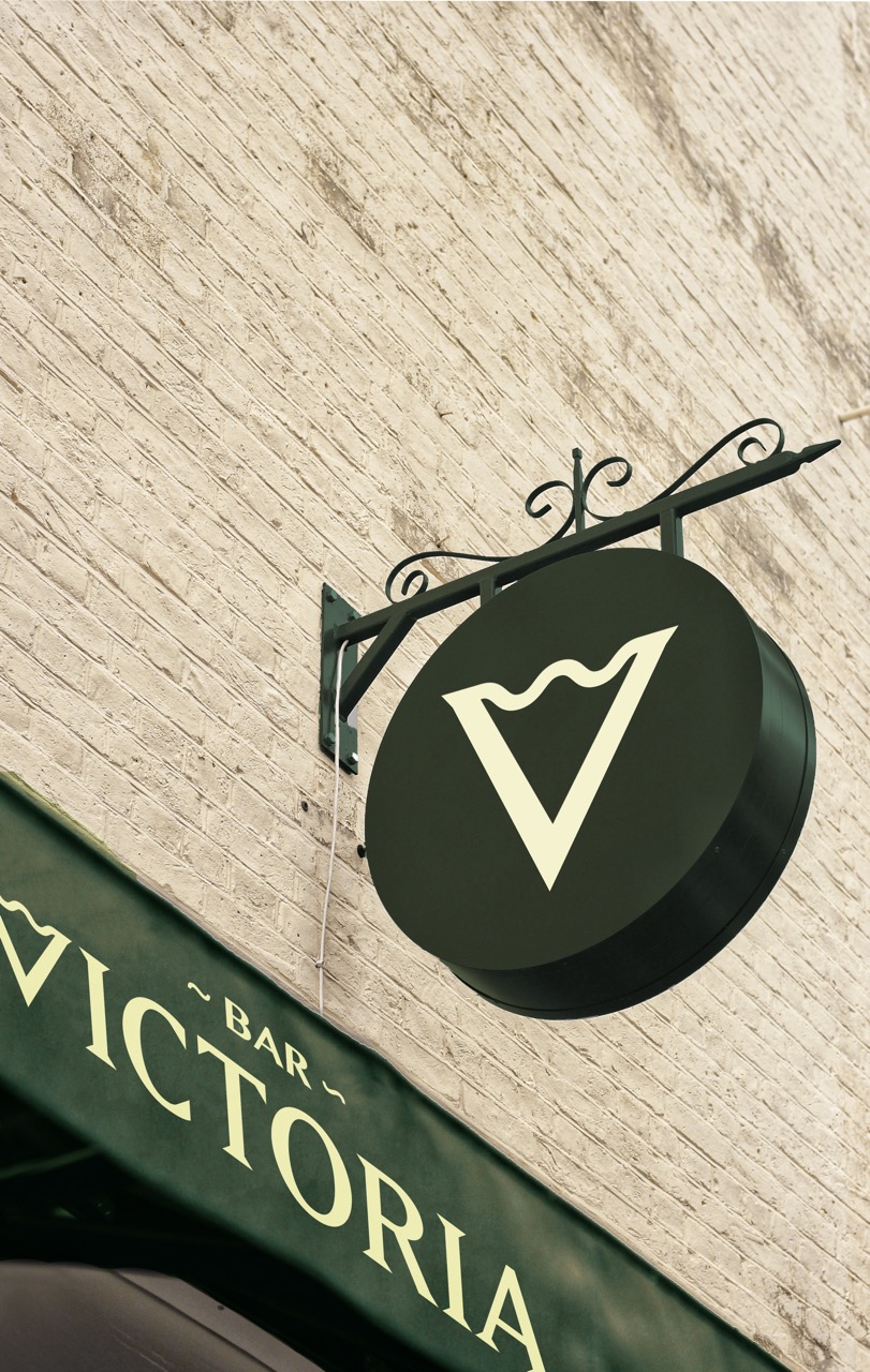 Graphic Communications work by Daniel McBrien. The letter V with the wave on a black sign hanging off a wall. With the full logo on a shop overhang underneath.