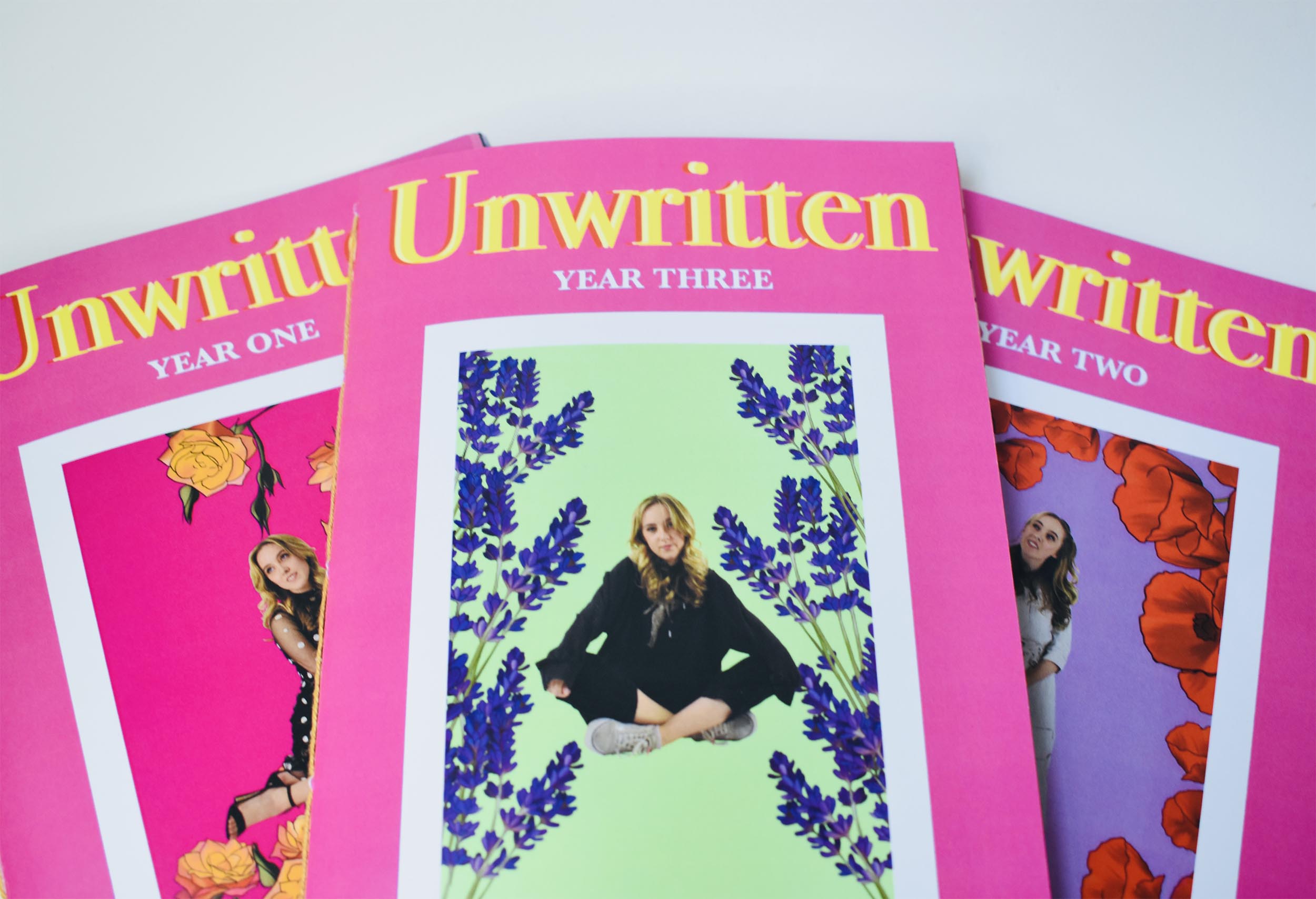 Three Zine covers spread out displaying a bright pink background and yellow font. Each zine has a different image of a girl surrounded by illustrated flowers.