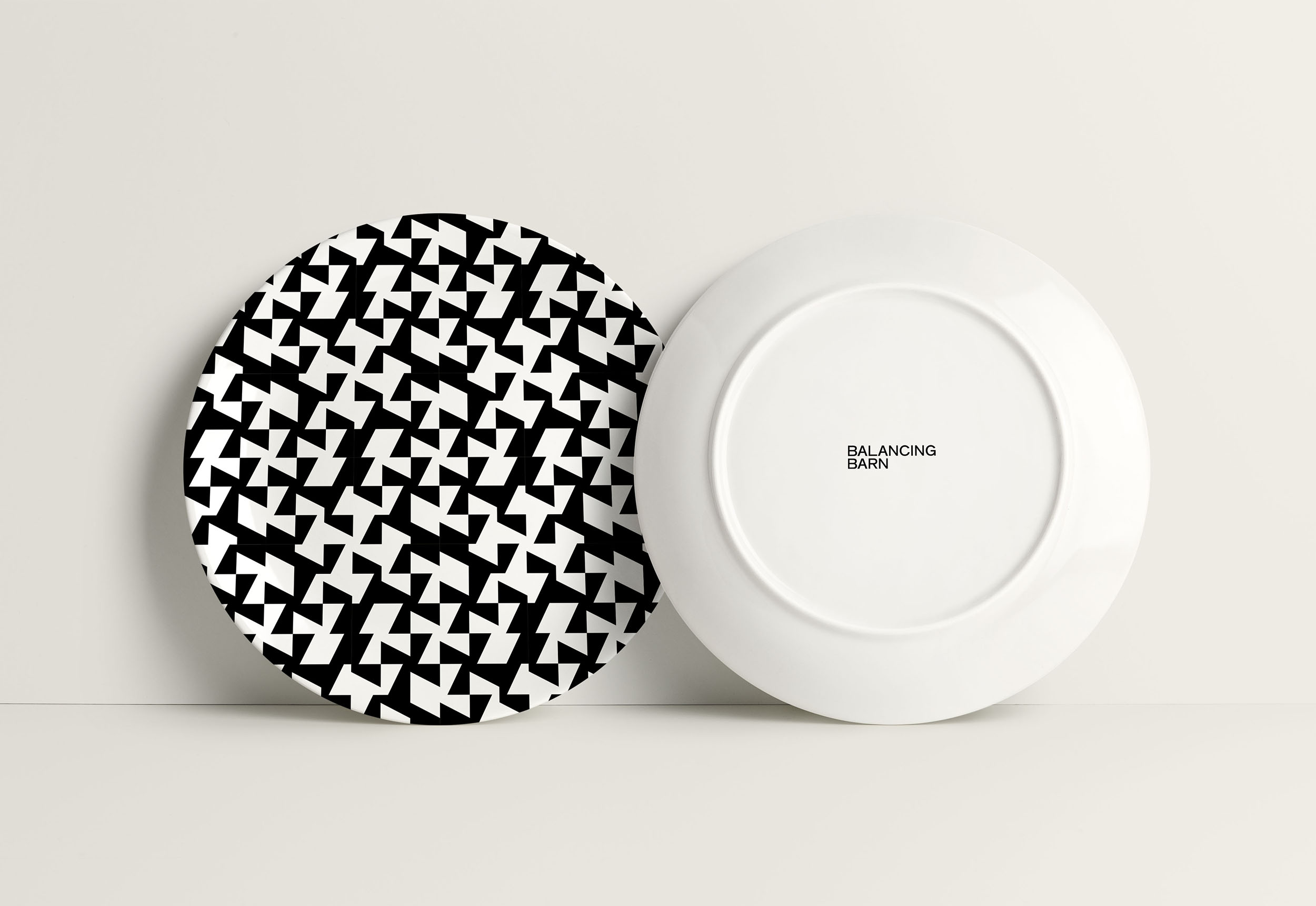 Graphic Communication work by James Keeley showing Balancing Barn Plates front and back. The front of the plate has a black and white geometric pattern, on the back of the plate is the Balancing Barn logo.