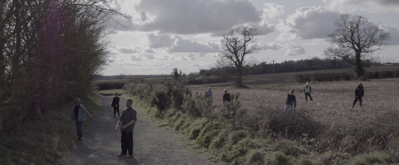 BA Hons Film and Moving Image, The One Percent, produced by Joanna Lambert, showing a still from the short film featuring a shot of several zombies in a rural environment.
