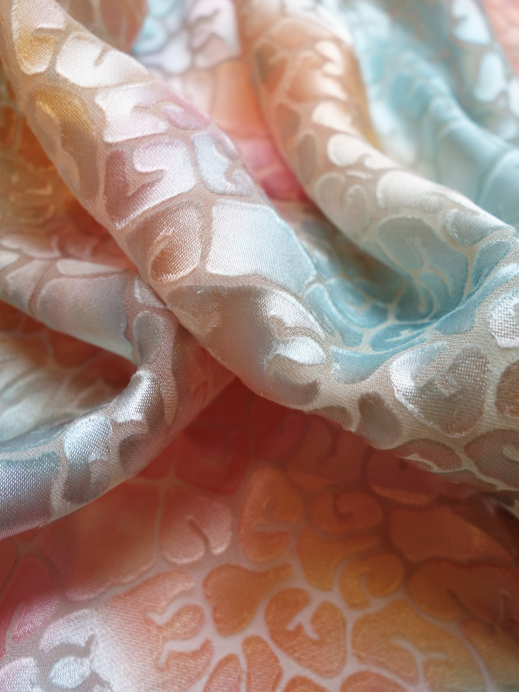 Textile sample close -up created by BA Textile design Graduate Marna Alberts. Soft and sweet gradients of peach, sea foam blue and sunset pink with an endless delicate textural pattern.