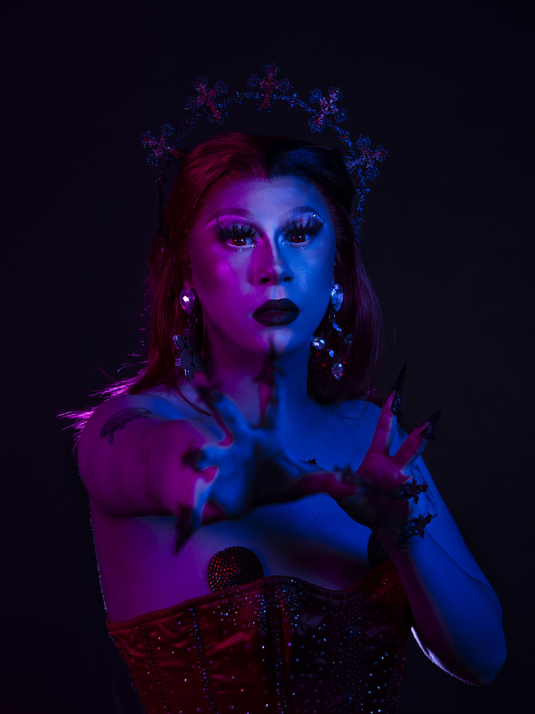 BA Photography work by Micha Hollis showing a portrait of drag artist Isla White. The lighting is multi-coloured with pink on the left and blue on the right.