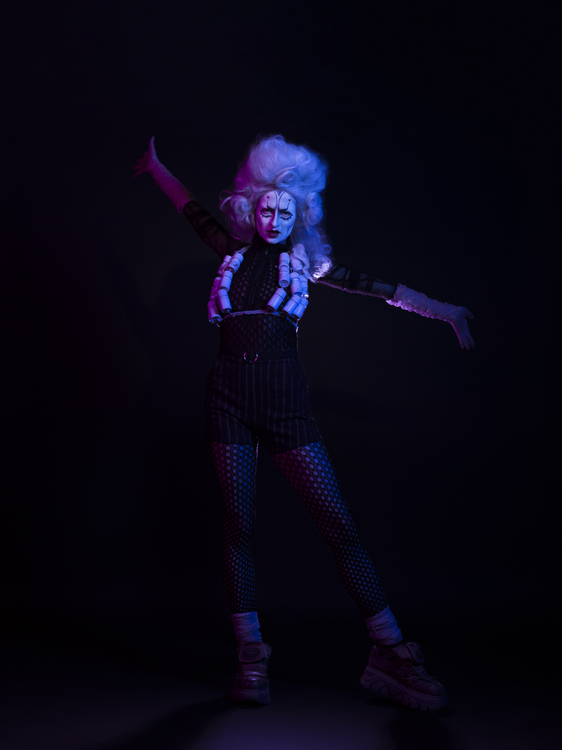 BA Photography work by Micha Hollis showing a portrait of drag artist Discount Dandy. The lighting is multi-coloured with pink on the left and blue on the right.