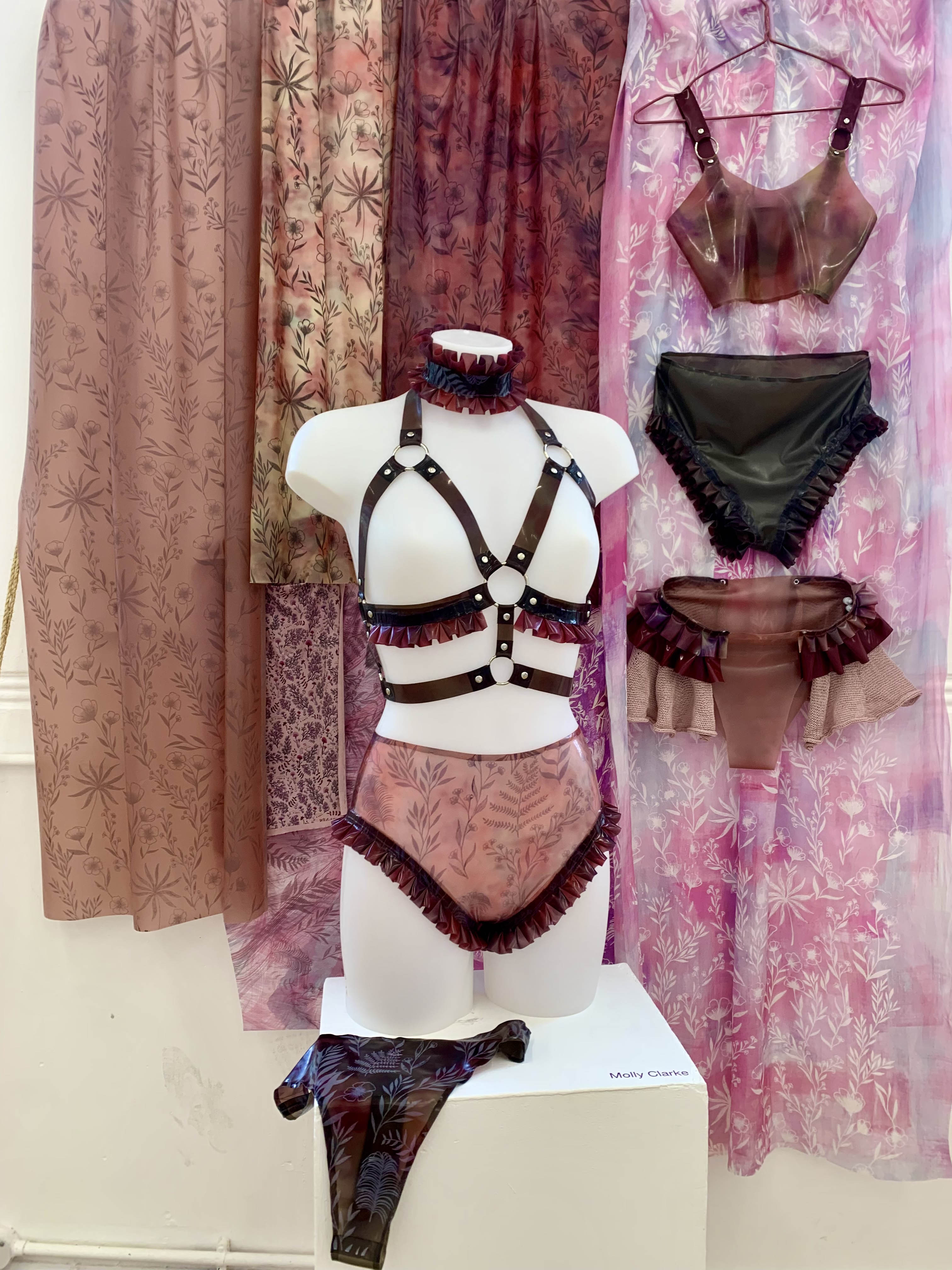 A collection of botanical screen printed samples on latex and silk, colourful printed designs on a watercolour like background, and hung garment made of printed latex.