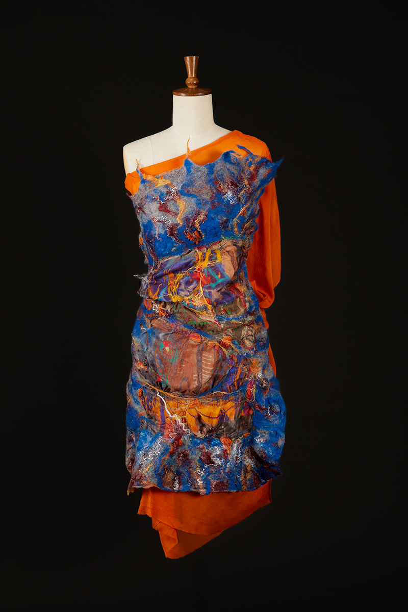 Graffiti patterned blue silk fabric backed on orange fabric draped on a mannequin.