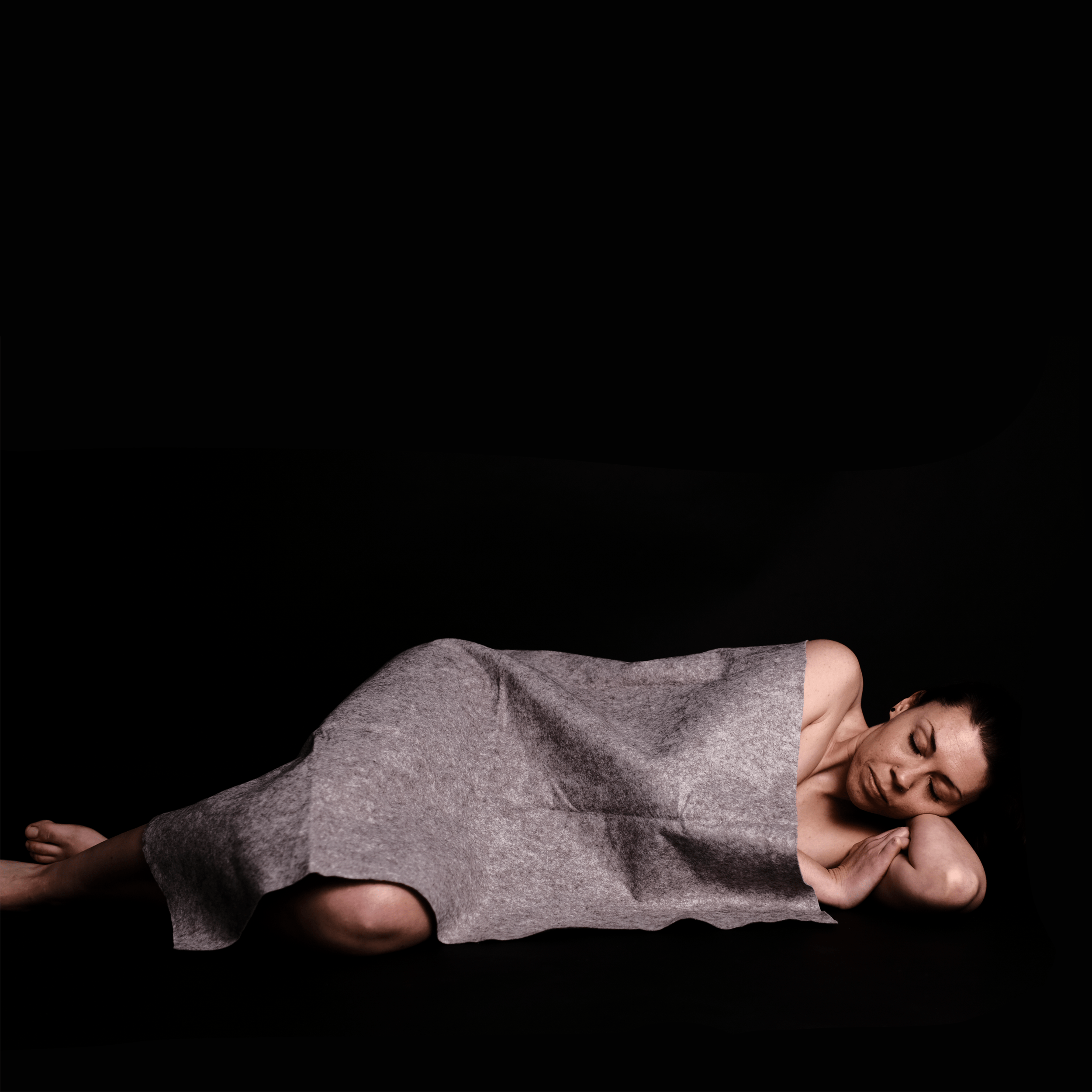 Photograph by Layne Howlett and Alice Collins showing a woman lyind down with a felt sheet covering her.