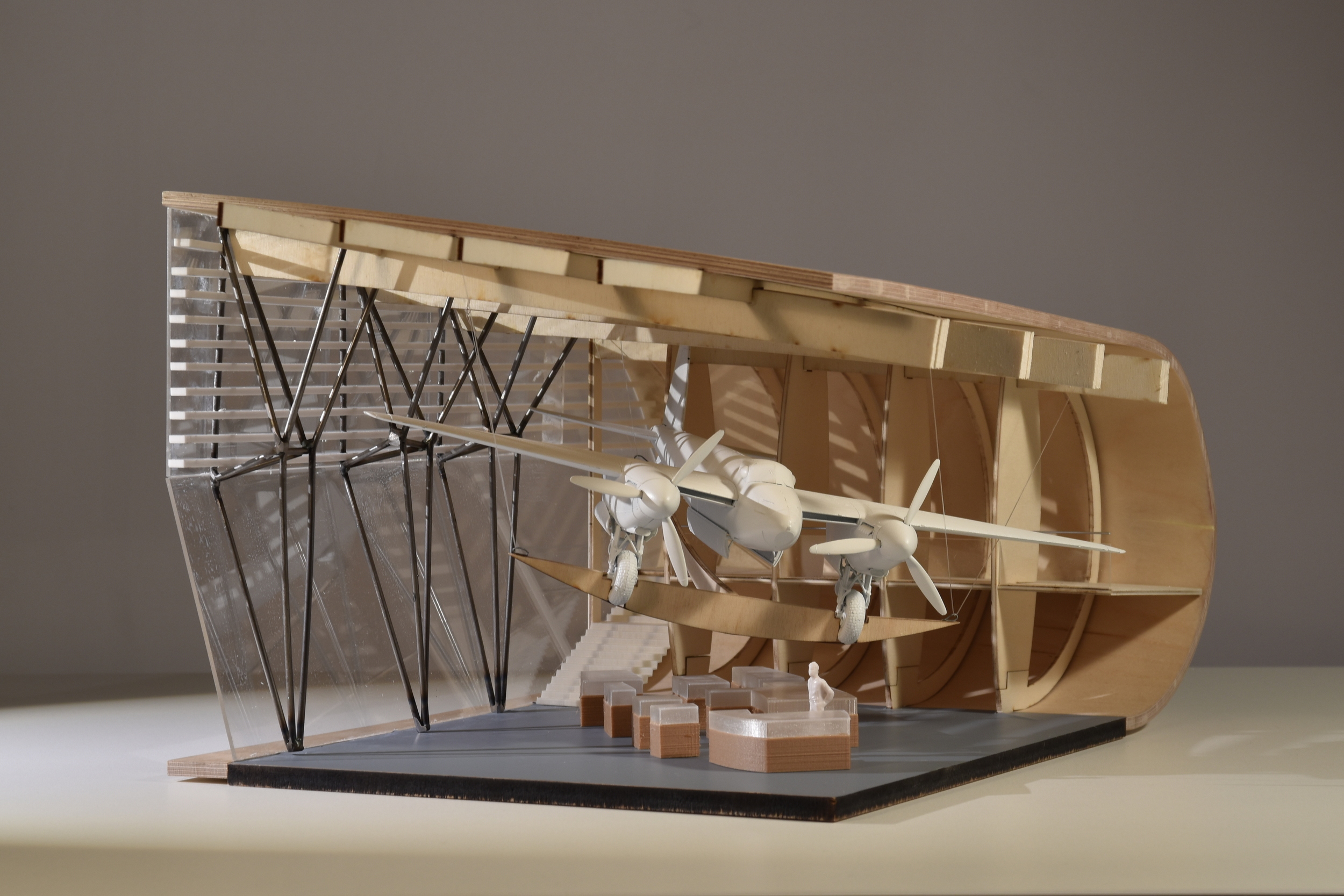 Final exhibition-grade model. Physical model is of an hanger exhibition space with a plane hanging from the ceiling and display cases below.