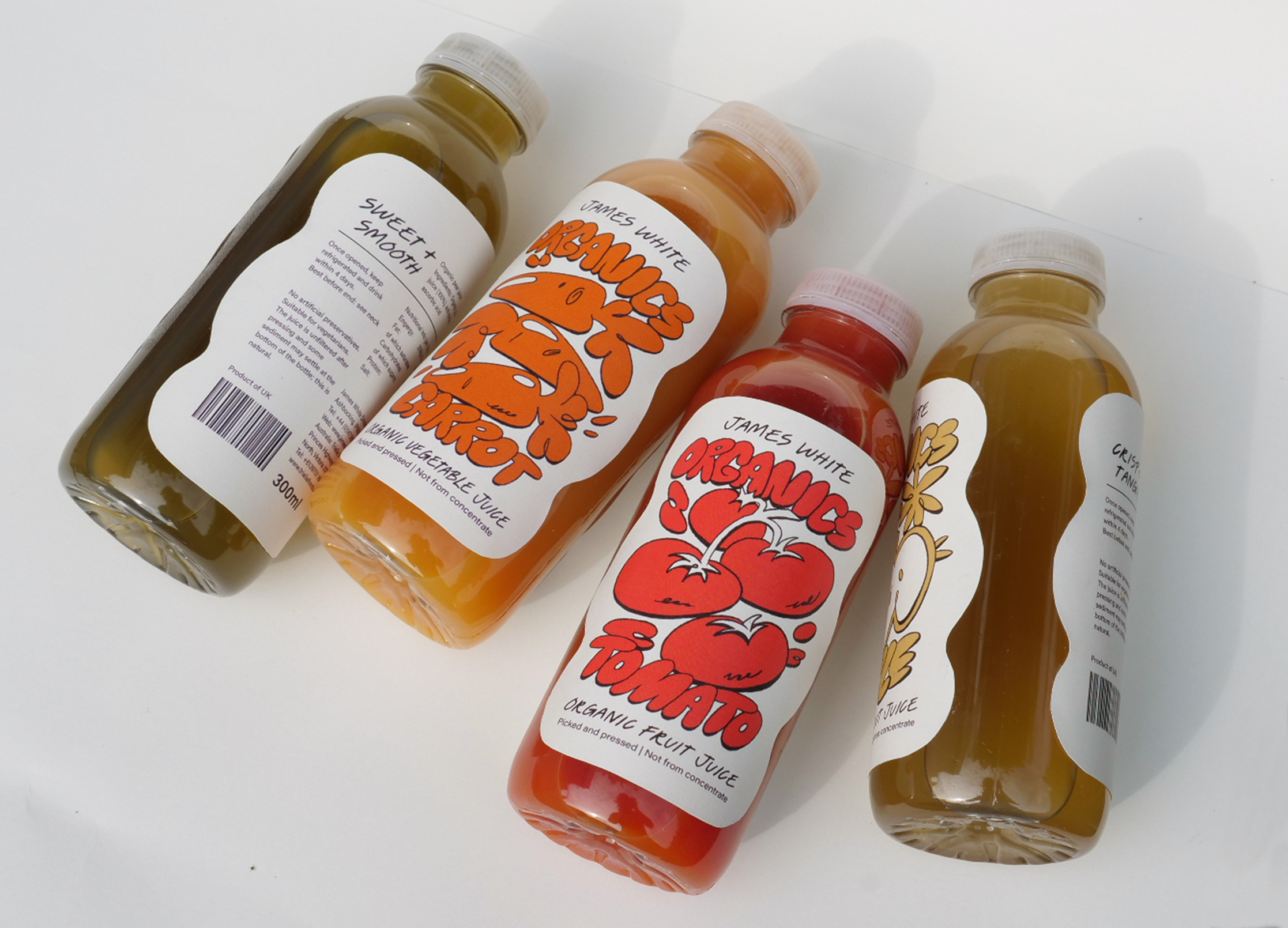 Photography of packaging design by Andrea Hammersley showing four organic juice bottles, with illustrated labels cut to organic shapes.