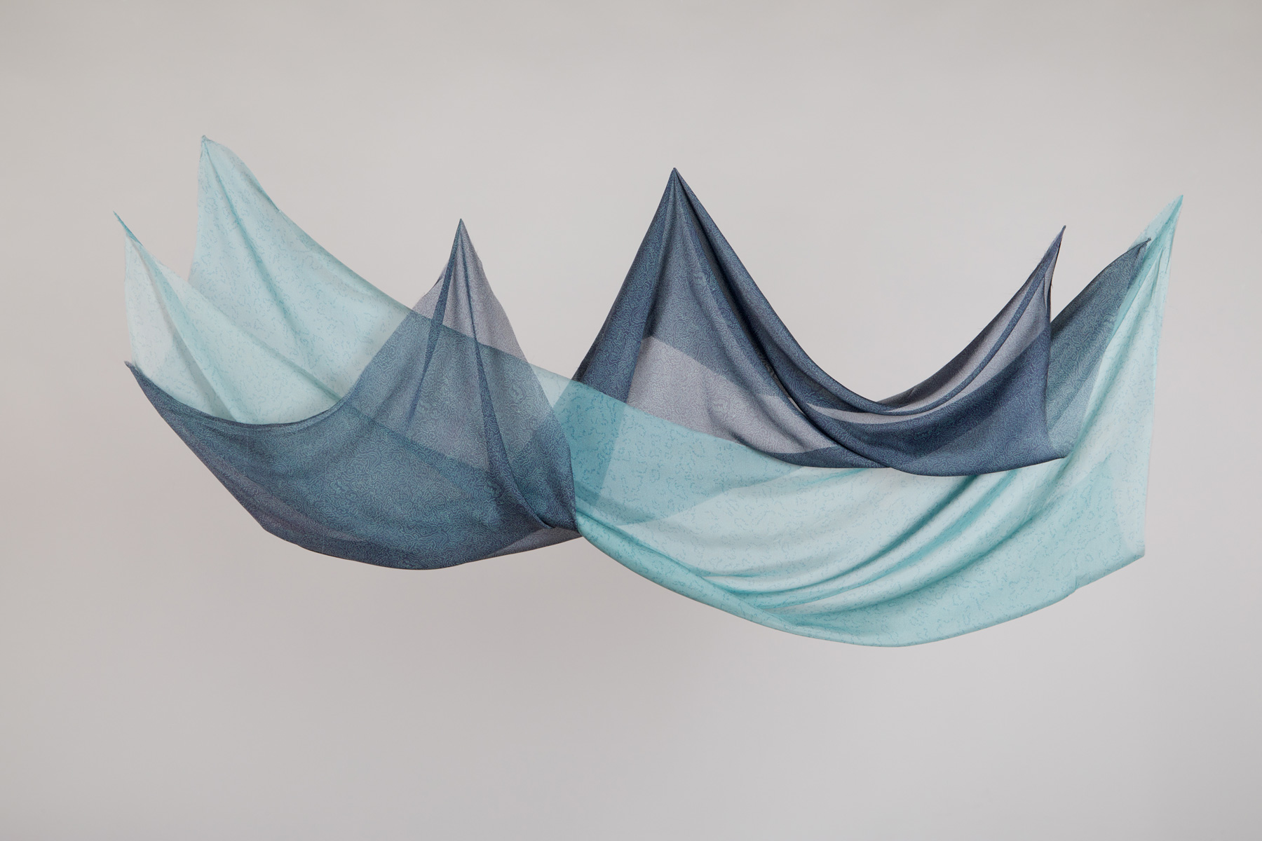 Photograph showing fluid light blue and dark blue silk suspended prints by Annabel Rowe.