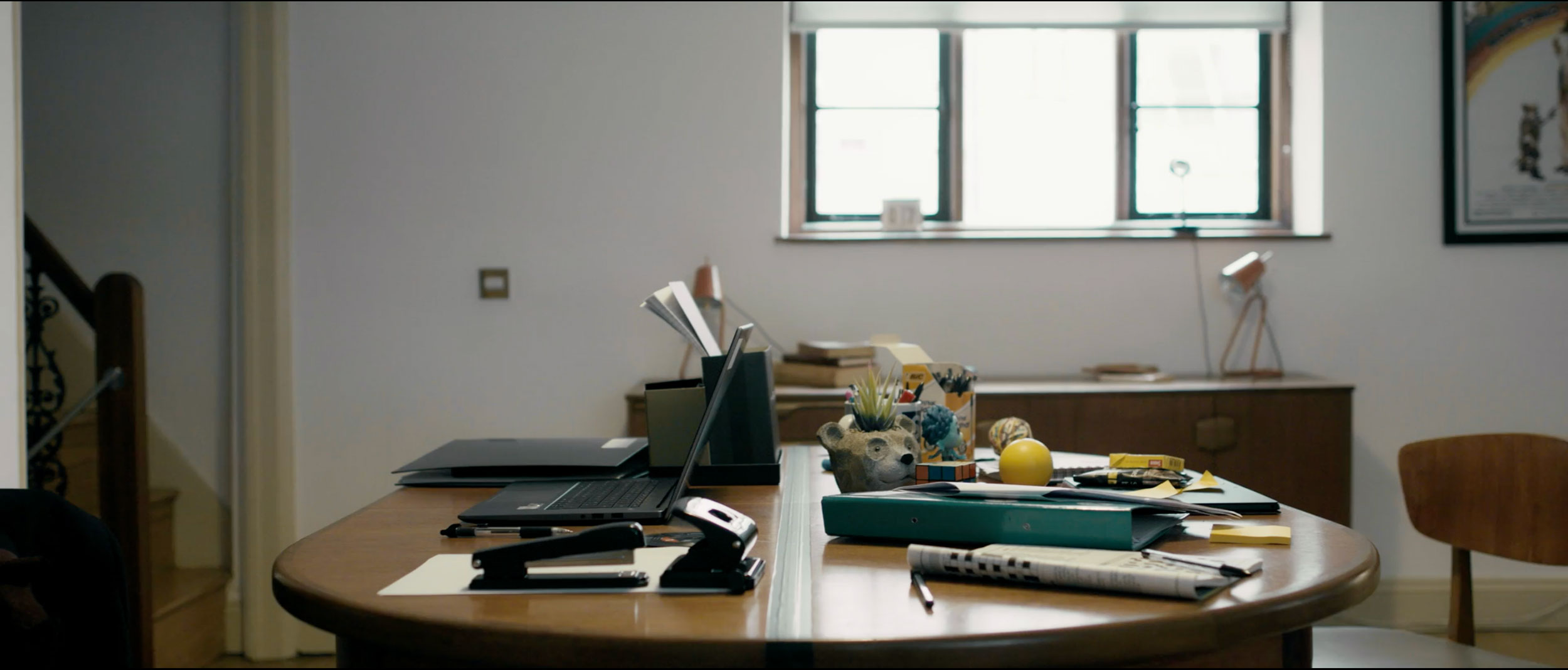 Still from Working Title directed by Lewis Cliff featuring a table with a laptop and office stationery