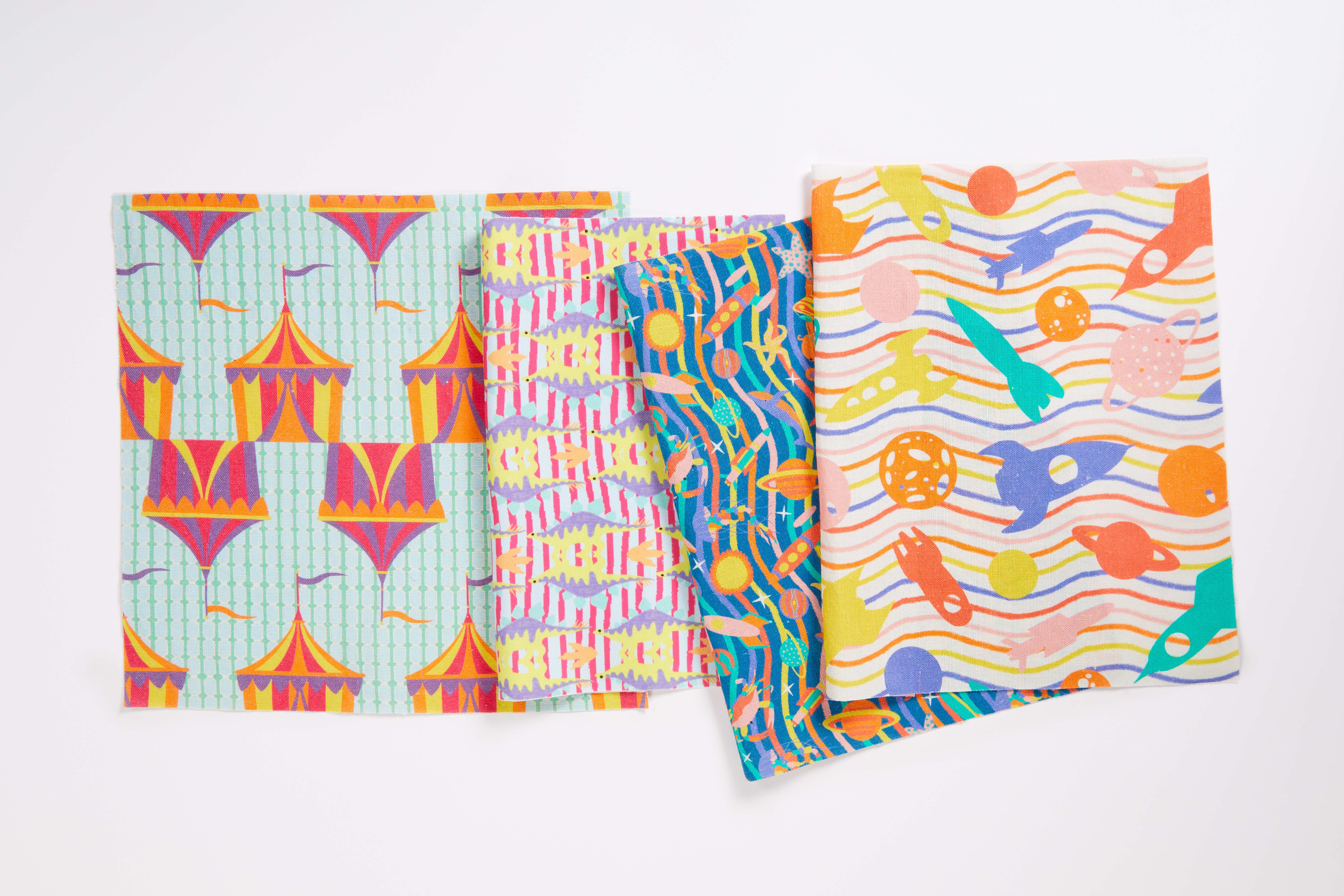 Photograph of 4 colourful fabric samples on white background lying flat.