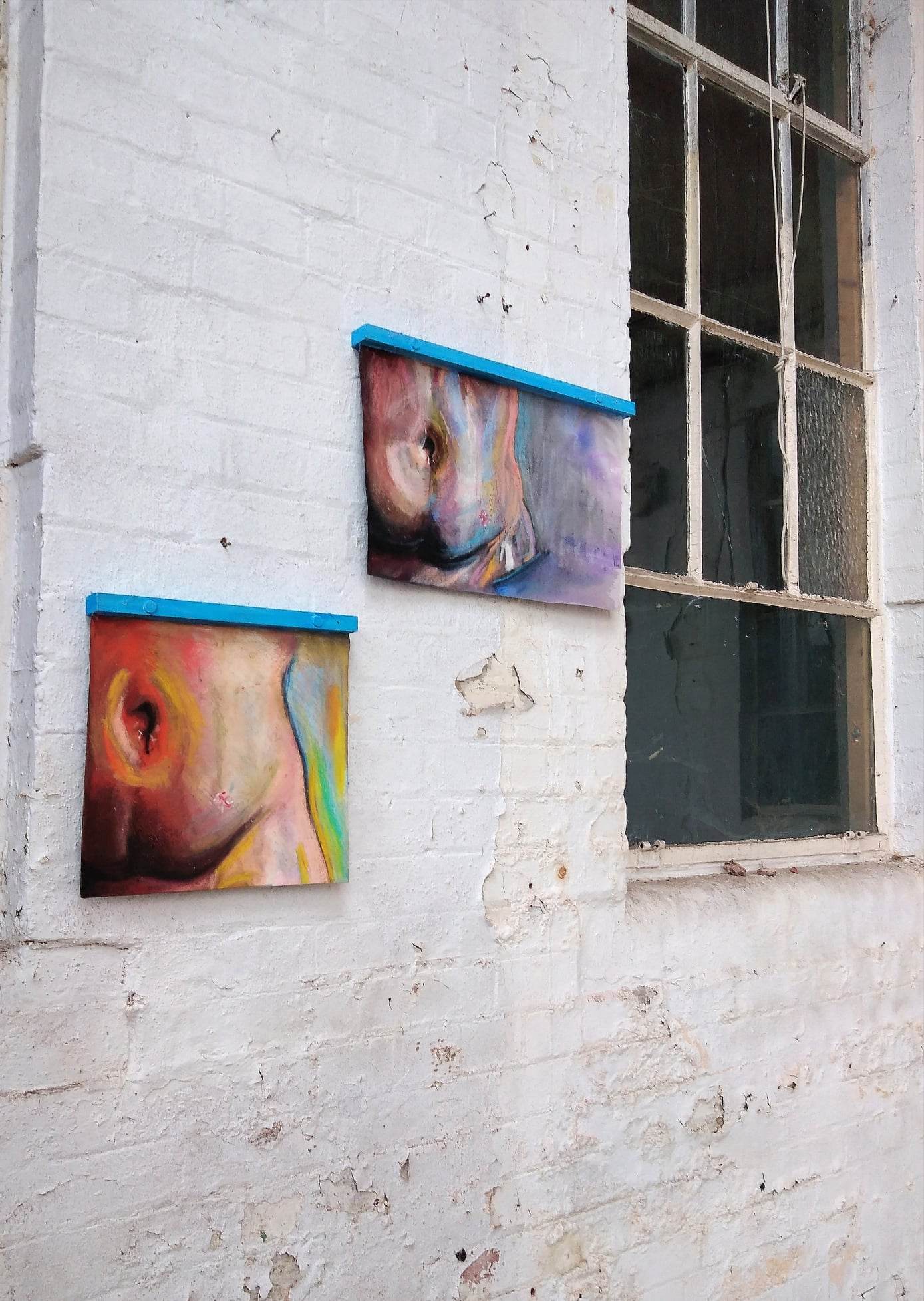 A diptych piece featuring different angles of the abdomen, displayed against a white brick wall next to a window.