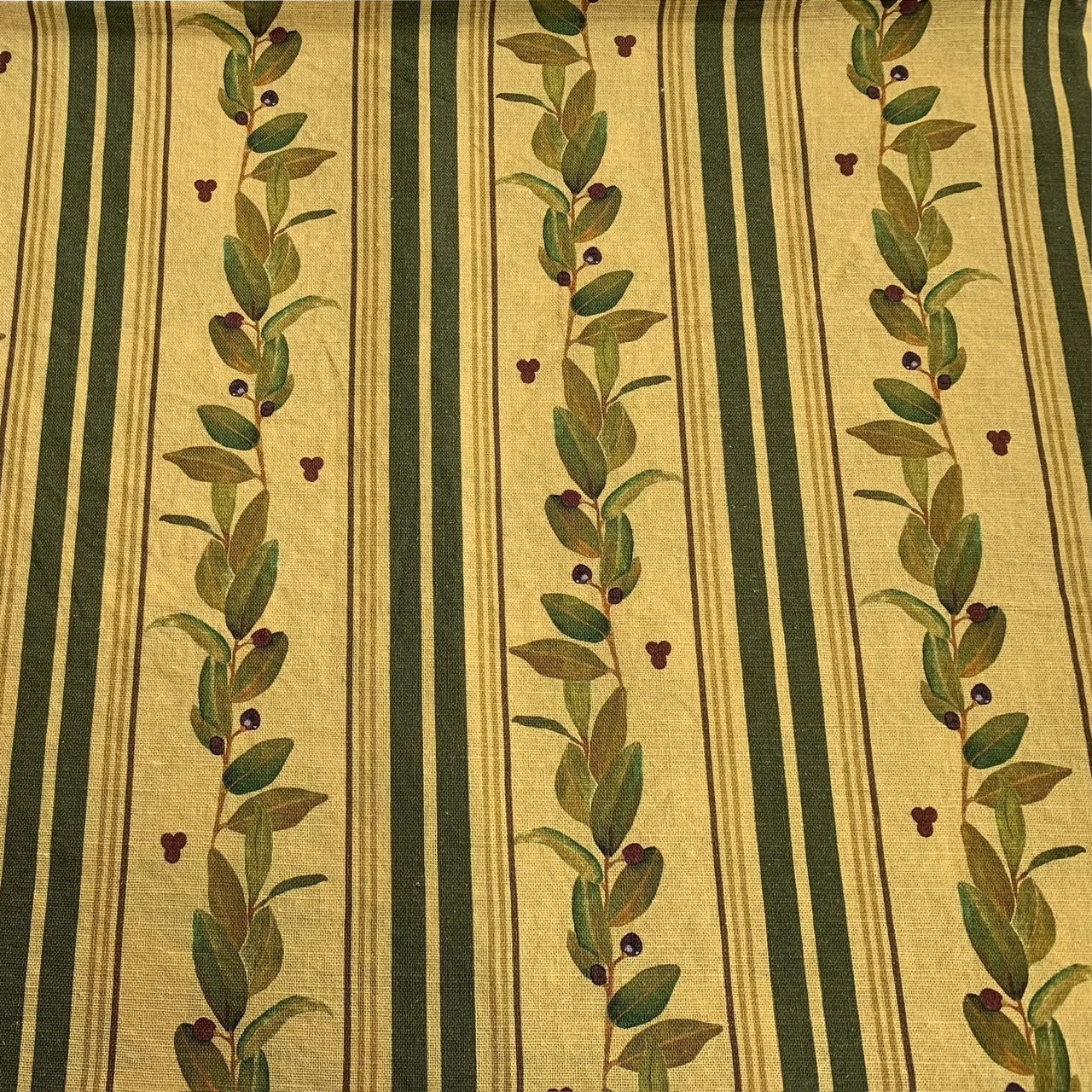 A repeat pattern printed onto a cotton-linen fabric with neutral colours, including a rich beige background, with striking deep green stripes, motifs of leafy green plant.