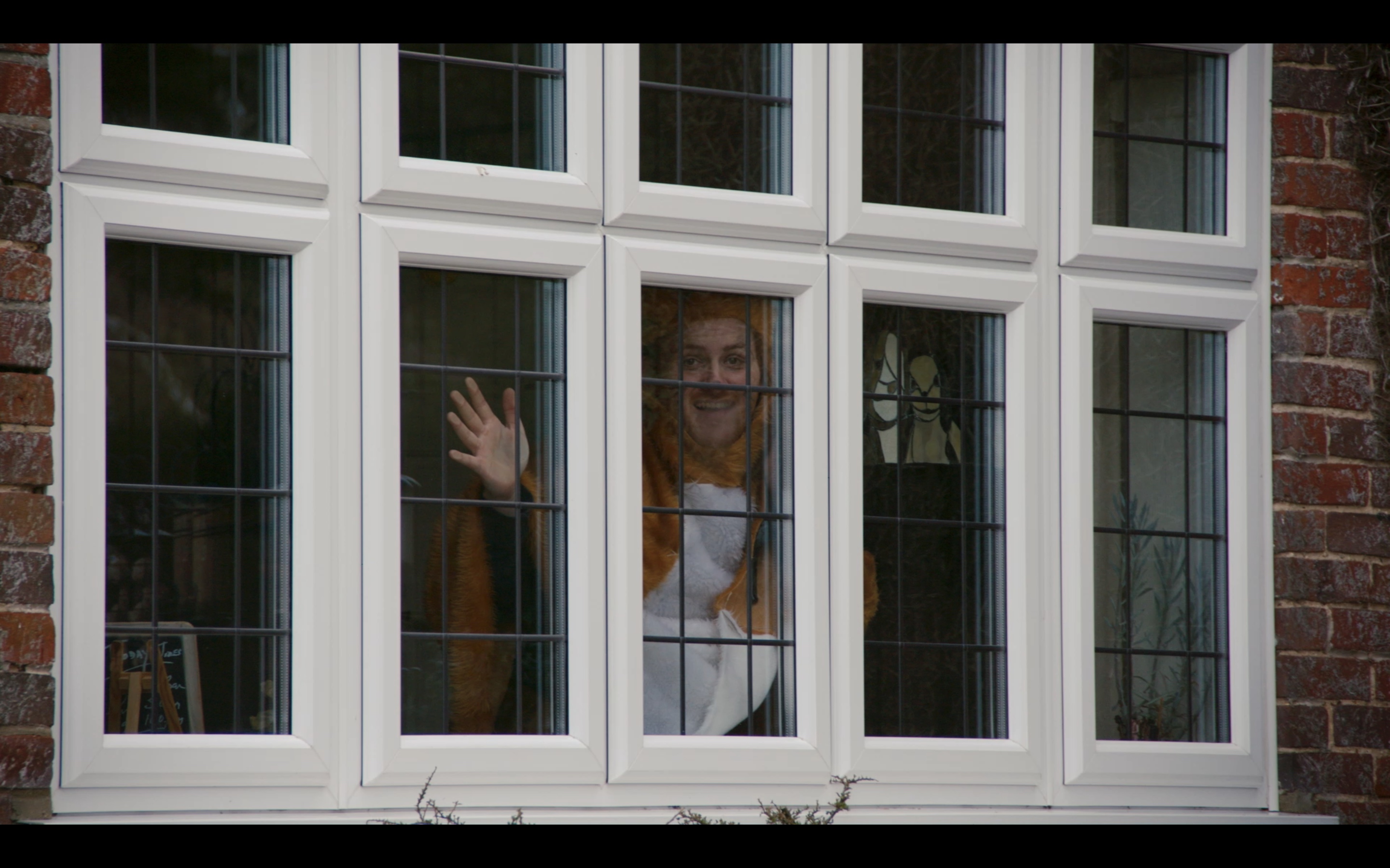 An image link to an extract from a short film in mockumentary style, directed by Finlay Renton featuring a character looking through a window.