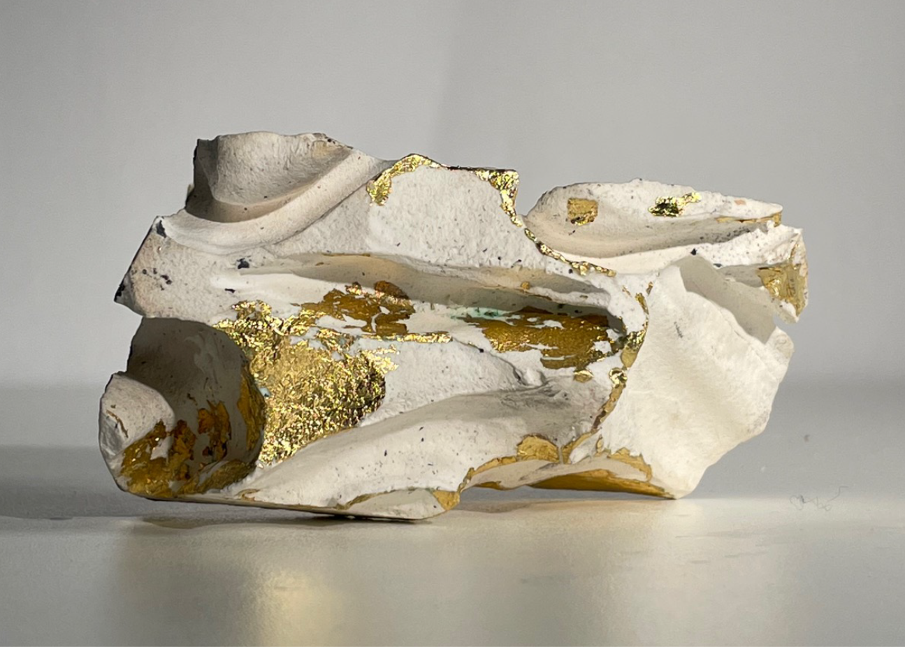 3D plaster sketch model inspired by flint, made by Georgia Keeble. The plaster shows intricate, sharp lines and details with a gold leaf that accents certain parts.