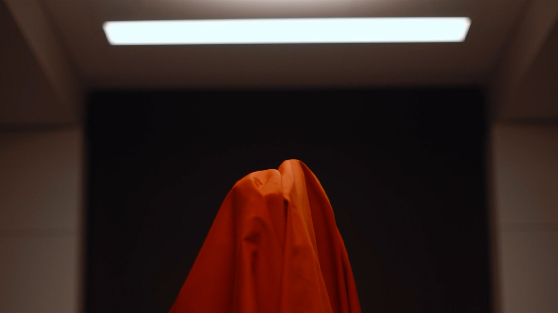 Still from the short film 'Aperture' showing a figure bathed in a red Cloth.