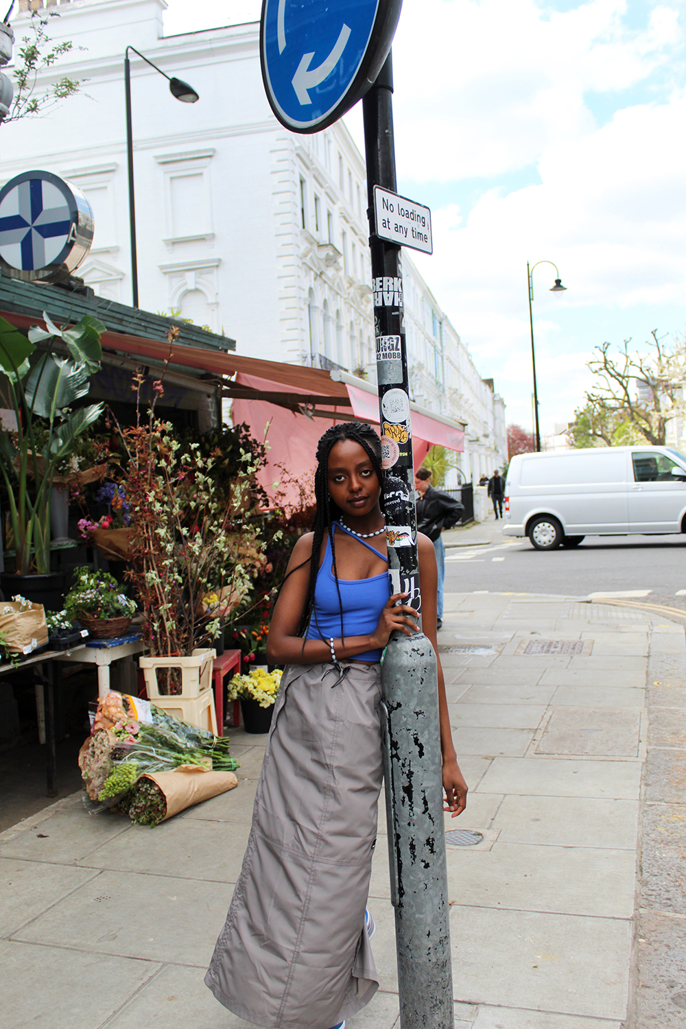 Fashion Portrait of model leant against road signage pole infront of flower shop by Katie Healy exploring African & Caribbean Influence on Fashion in Britain