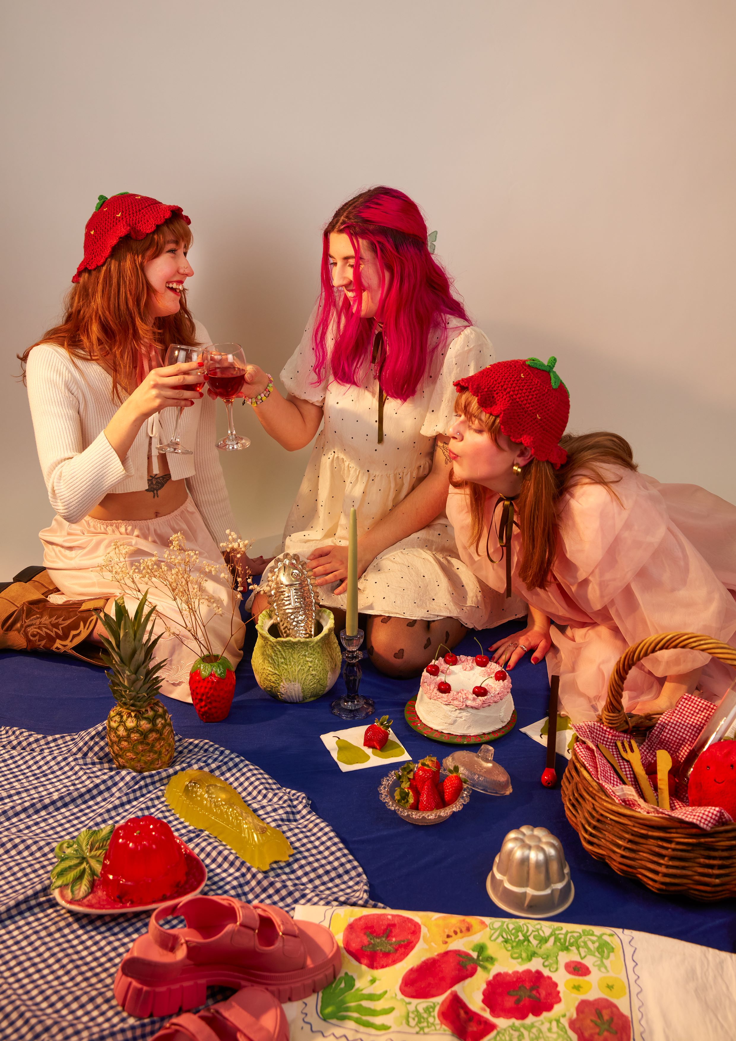 Photoshoot of Laura's strawberry hats in a dreamy picnic scene.