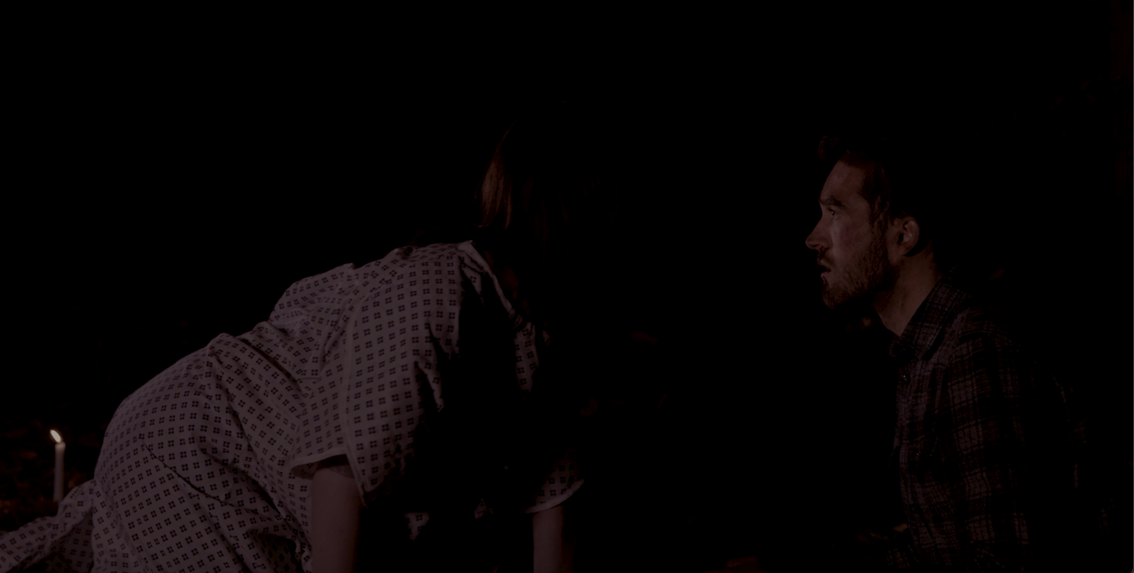 A still from a short horror film with two characters facing each other in the dark