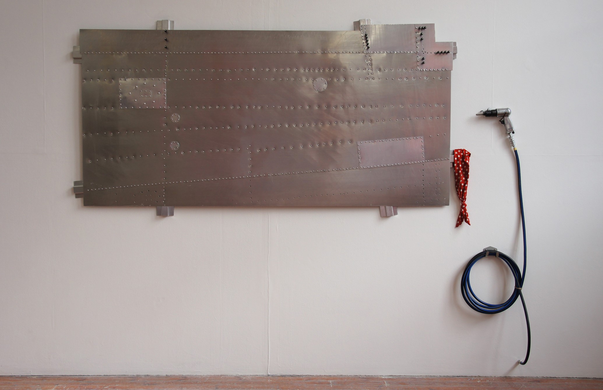 A metal sculpture by Marek Jeczalik. A large section of Aircraft hangs on the wall with tools.