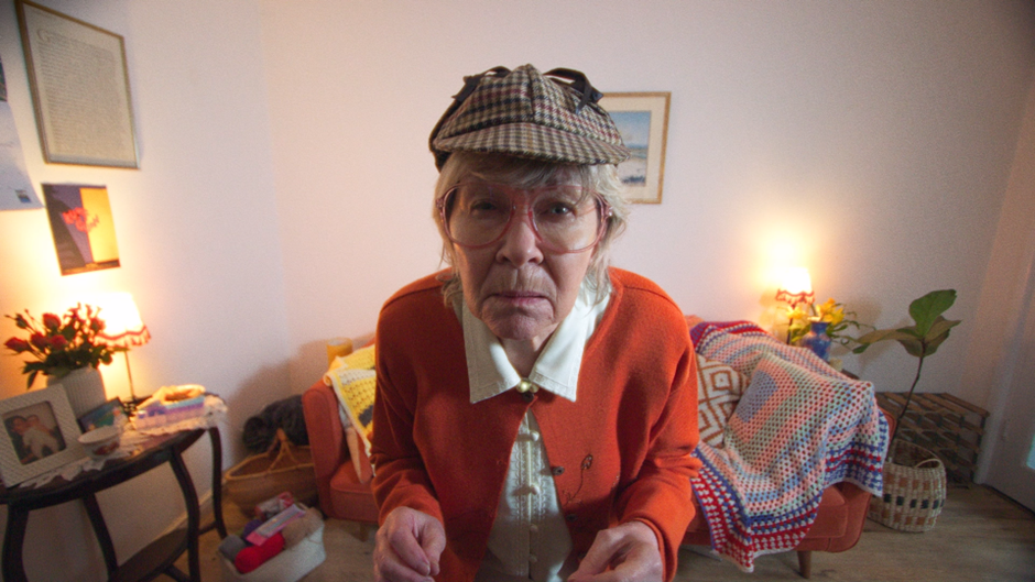 Image of an elderly woman investigating with a look into camera wearing a dear stalker hat