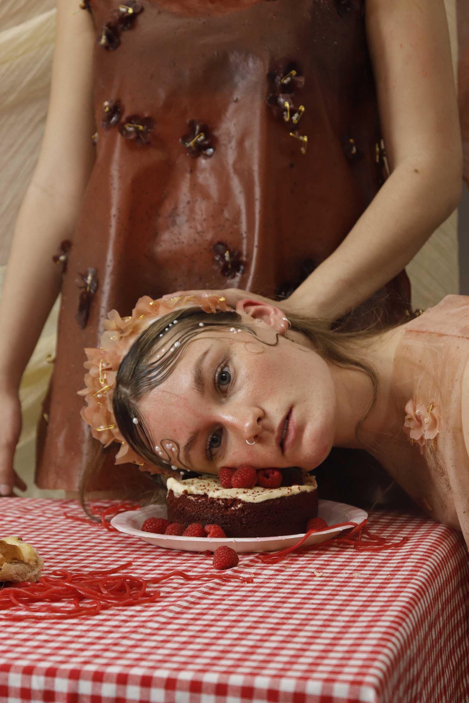 BA Fashion Design work by Mollie Green showing a young woman getting her faced pushed into a cake at a messy picnic scene