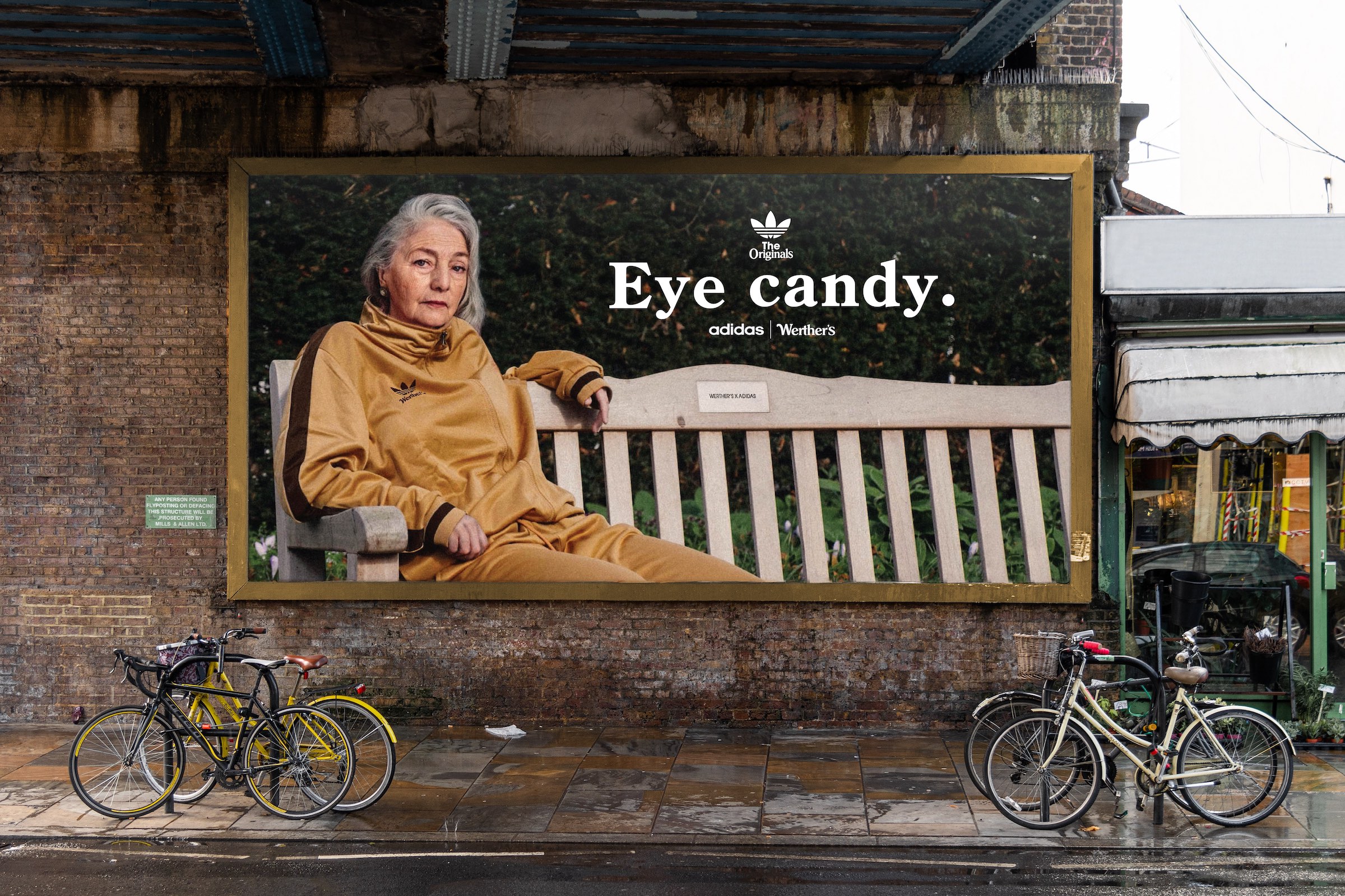 A billboard containing an image of an older lady posed on a bench wearing a gold Adidas Originals tracksuit.