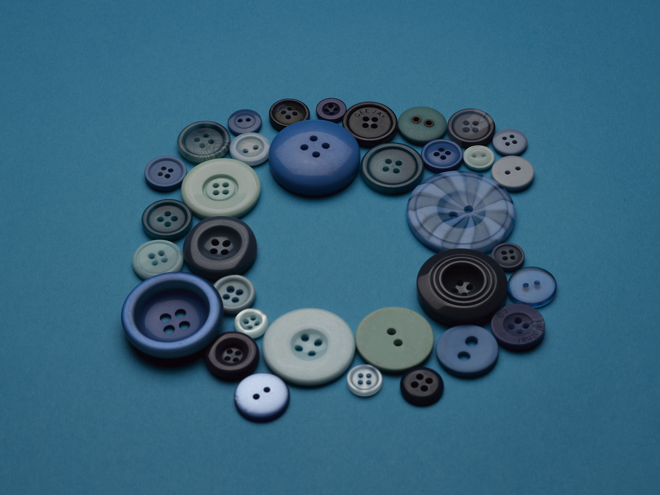 Photograph by Rhianna Cleaveley of different shades of blue buttons forming a square shape.