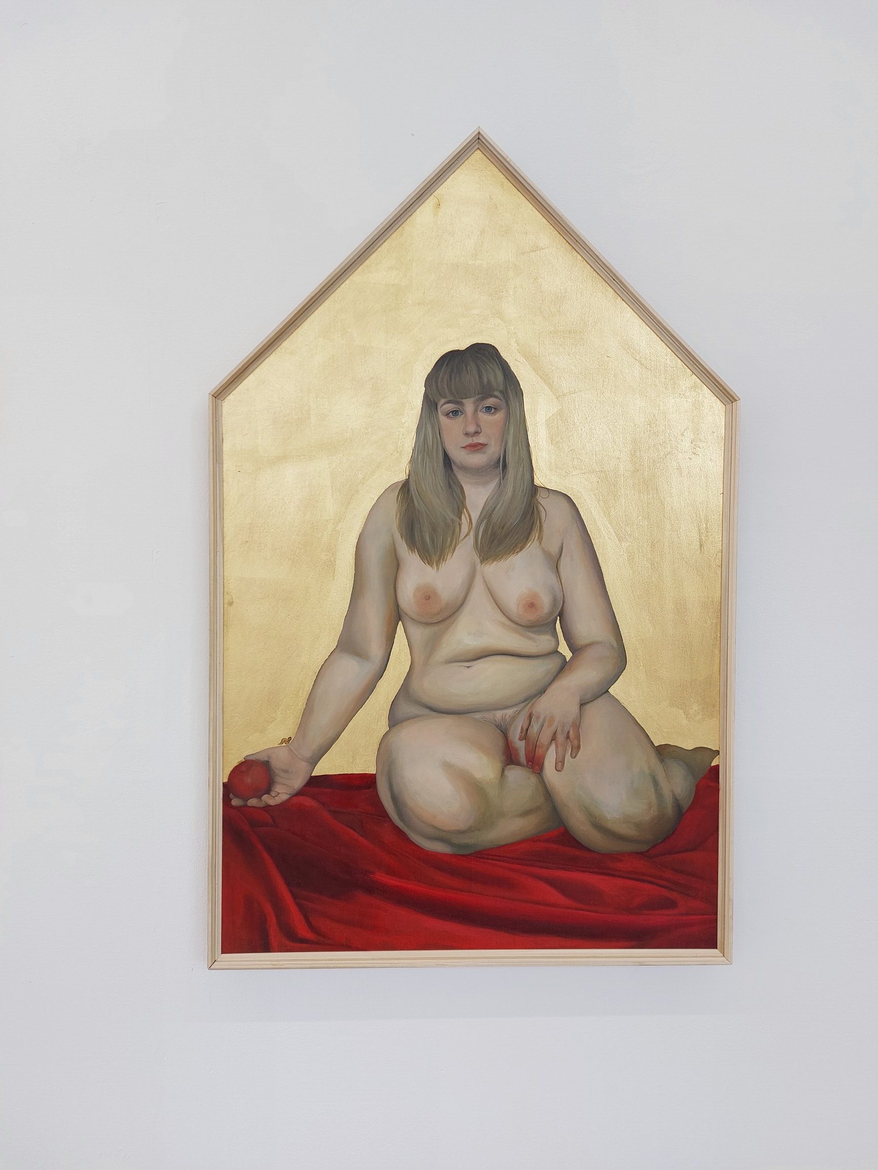 Oil painting of a blonde, nude female figure as the biblical Eve, holding an apple in one hand with blood on the other and on her thigh, sat on a rippling red sheet with a solid gold background.
