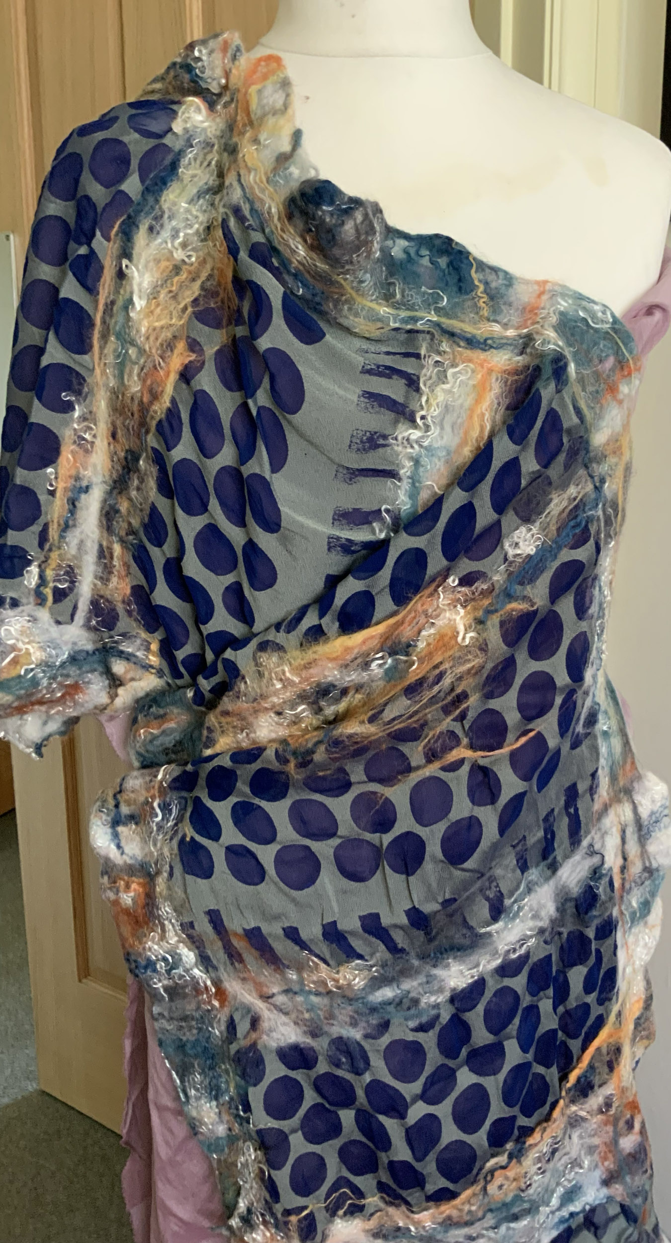 A blue and grey scarf using devore techniques draped over a mannequin.
